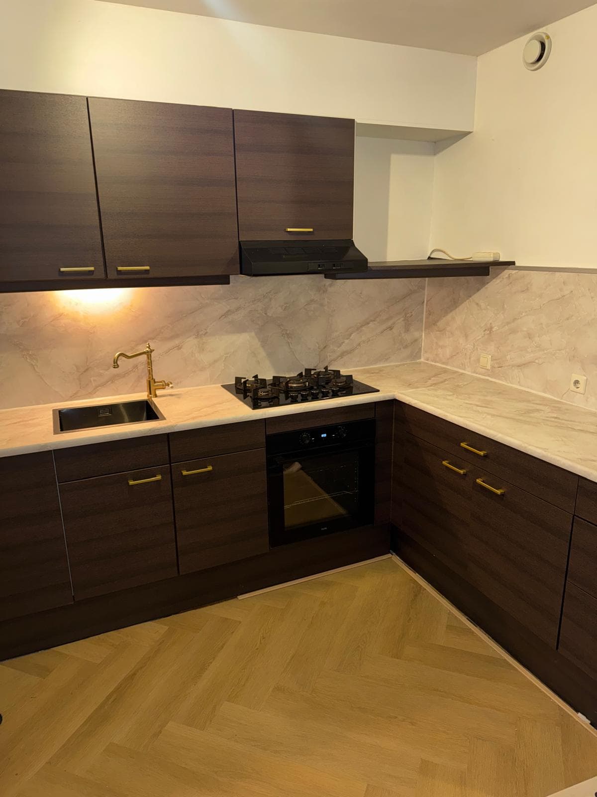 Donkere houtlook keuken met marmerlook werkblad en gouden kraan