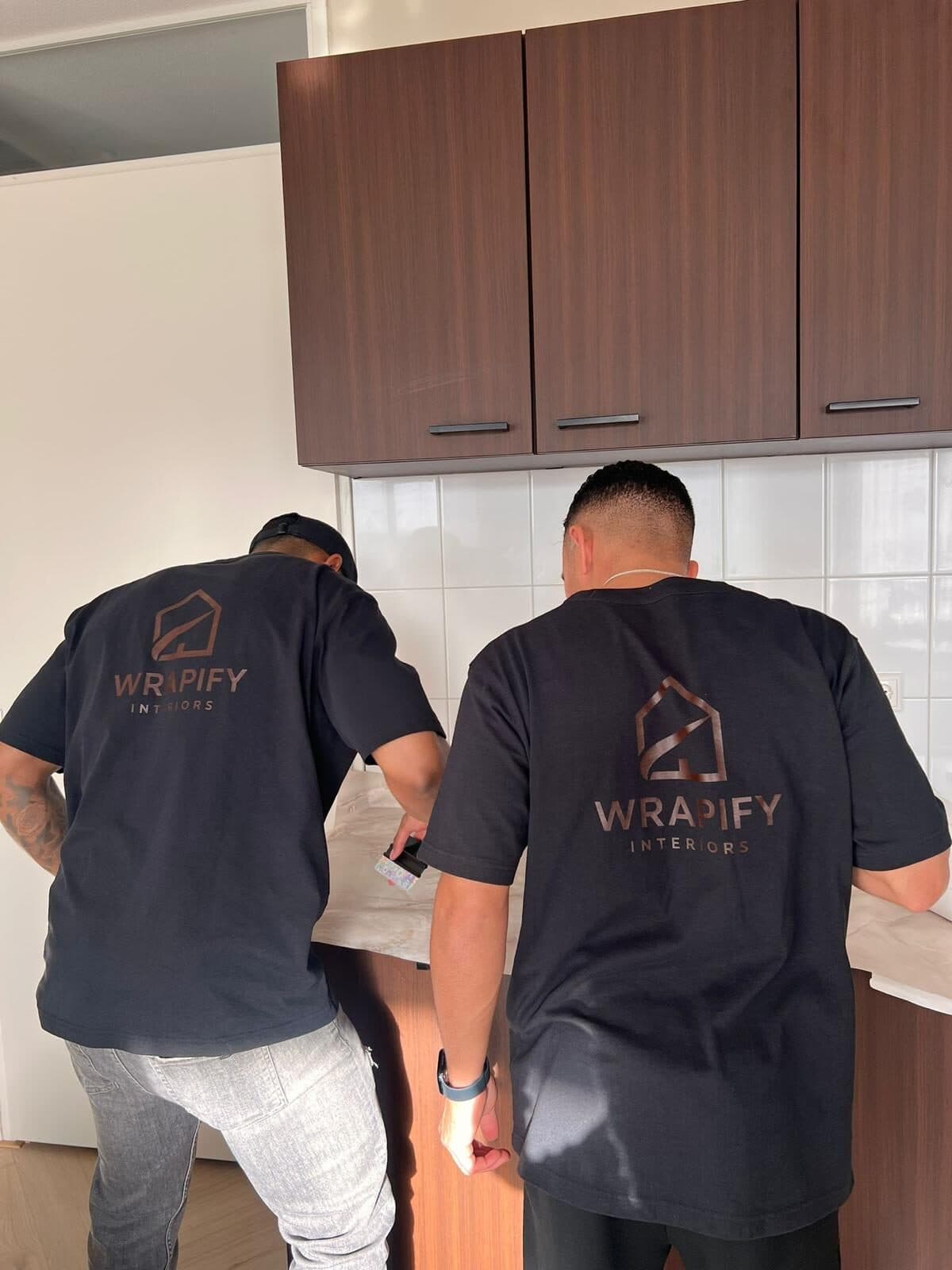 Twee monteurs van Wrapify Interiors in bedrijfskleding wrappen een keuken op locatie
